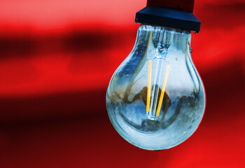 Glass bulb with socket on an red black background. Abstract concept image of colorful light lamp glowing against orange tones. innovation, technology, futuristic concept. Copy space
