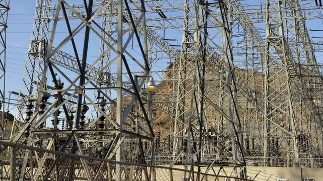 High voltage power lines are prominently displayed at Hoover Dam, capturing the intricate structure against the backdrop of a blue sky in Arizona Nevada.