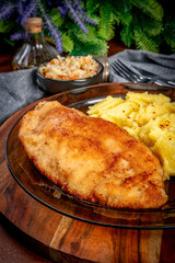 Breaded chicken breast fillet served with boiled potatoes and salad.