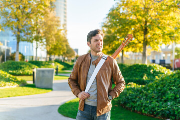 Fototapeta premium Man in the park with guitar on his back.