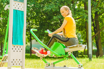 Girl doing exercises outdoor, holding phone