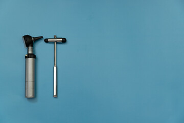 tuning fork C 128 on a blue background with gradation and otorhinoscope and neurological hammer