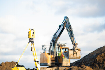 Construction site with surveying equipment in use alongside heavy machinery