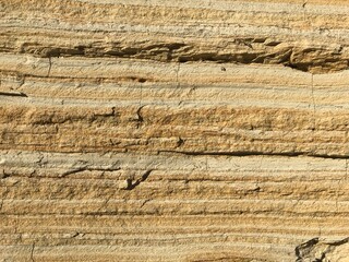 Close-up of layered sandstone showing horizontal striations and varying shades of tan, brown, and beige, revealing natural sedimentary rock patterns formed over time.