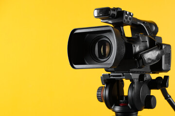 Modern video camera on yellow background, closeup. Space for text