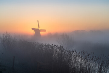 Dawn at a traditional, Dutch windmill in the spring fog.