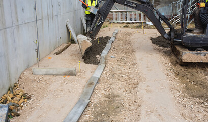Builders laying concrete edging curb blocks on semi-dry concrete