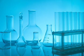 Laboratory glassware on mirror surface against light blue background