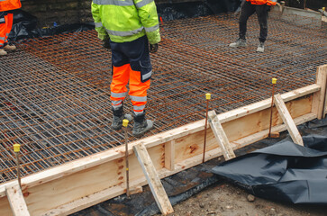 Steel fixers builders lay rebar and prepare concrete foundation at construction site