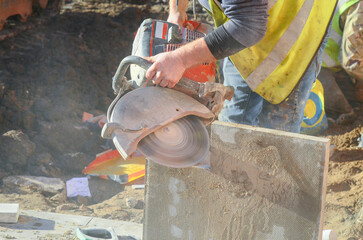 Construction worker using a concrete saw to cut concrete paving slab