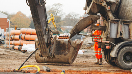 Discharging delivered concrete from mixer truck into excavator bucket