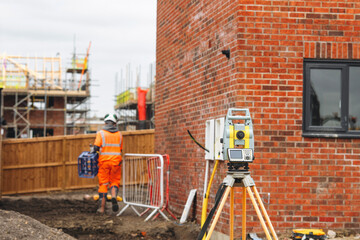 Construction worker using surveying equipment at building site