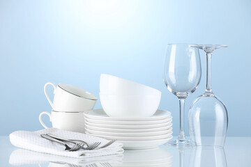 Different clean dishware on light blue background. Space for text