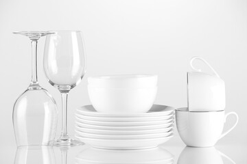 Different clean dishware and glasses on light background