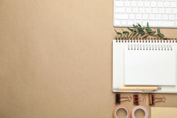 Binder clips, other stationery, computer keyboard and green branches on beige background, flat lay. Space for text