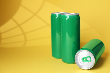 Three tin cans on yellow background with shadow. Space for text
