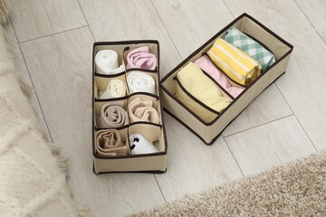 Organizers with folded clothes on floor indoors, above view