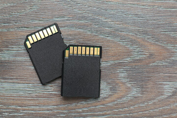 Two SD memory cards on grey wooden table, top view. Space for text