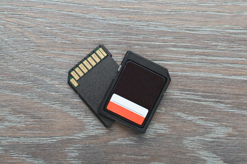Two SD memory cards on grey wooden table, top view