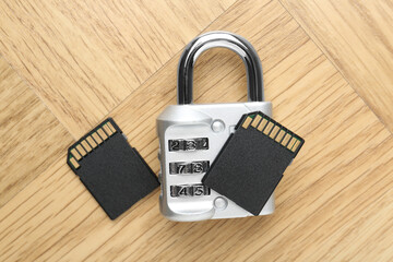 SD memory cards and combination padlock on light wooden table, flat lay