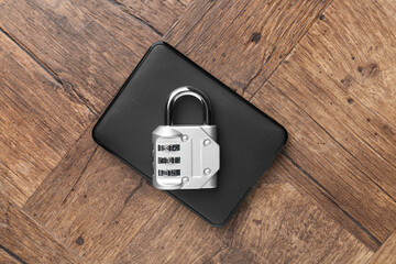 External hard drive and combination padlock on wooden table, top view