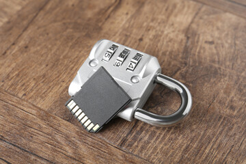 SD memory card and combination padlock on wooden table, closeup