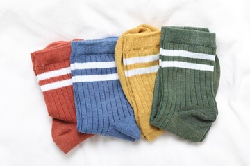 Different soft socks on white blanket, top view