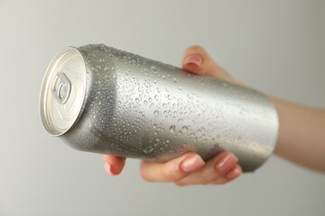 Woman with tin can on light grey background, closeup