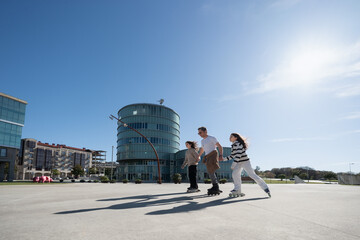 Father skating with daughters in city square on sunny day © asier