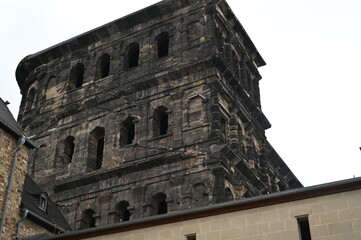 Obraz premium Ancient stone fortress wall with arched windows and weathered dark masonry. Historic Roman architecture creating a dramatic, timeless atmosphere.