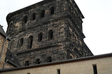 Fototapeta premium Ancient stone fortress wall with arched windows and weathered dark masonry. Historic Roman architecture creating a dramatic, timeless atmosphere.