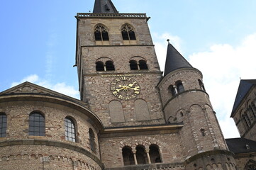 Fototapeta premium Historic stone towers and church spire against blue sky. Old European architecture with medieval walls and ancient facade. Travel, tourism, and cultural heritage concept.
