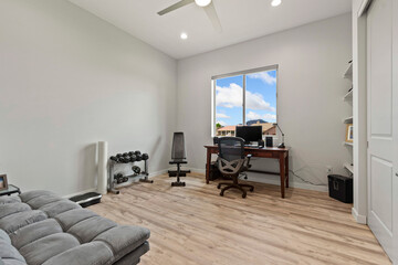 A cozy living room featuring a couch, desk, chair, and a window