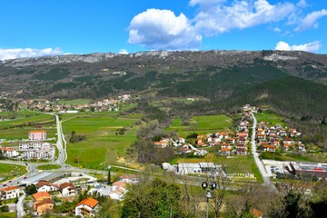View of residential areas and green fields of the town Buzet bellow forest covered mountains in...