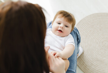 Adorable 7 month old baby laughing while lying on mother's lap, over the shoulder shot. mom and baby