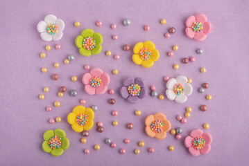 Easter decor for cake: colorful sugar sparkles and flowers on pastel purple background. Top view