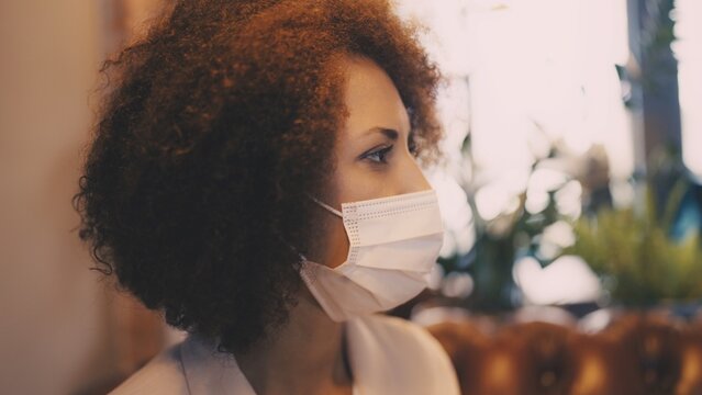 African American woman in face mask talking to friend, pandemic social interaction