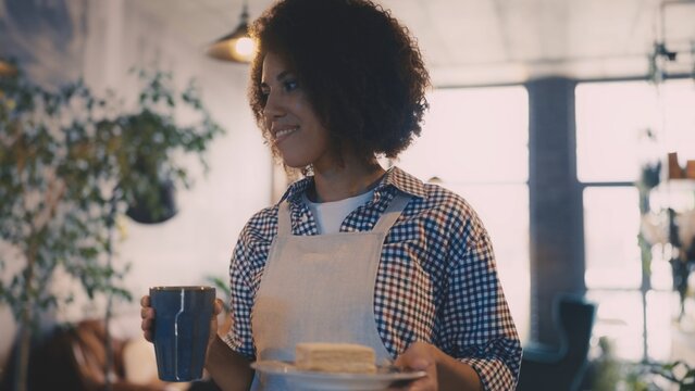 African American waitress serving coffee and dessert to customer in cafeteria