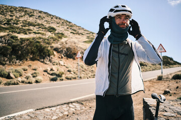 Cyclist takes a break on a scenic mountain road, adjusting his helmet and neck warmer.  Enjoy the...