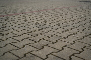 Fototapeta premium Gray concrete paving blocks arranged in zigzag patterGray concrete paving blocks arranged in zigzag pattern. Textured stone pn. Textured stone pavement for urban road, parking lot, or sidewalk design.