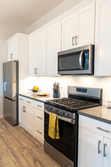 Fototapeta premium A kitchen with white cabinets, stove, refrigerator, and microwave