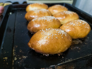 A tray of freshly baked buns with sesame seeds on top of them