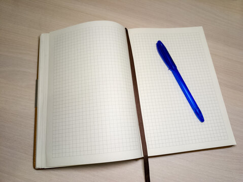 A notebook with a blue pen sitting on top of it