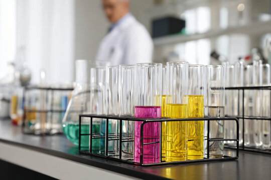 scientist in lab coat observing colorful chemical reaction in glass beaker