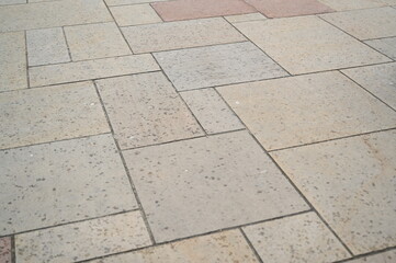 Stone pavement texture with rectangular beige and gray tiles. Urban sidewalk pattern ideal for architectural design, background, or construction materials concept.