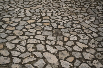 Old stone pavement texture with irregular cobblestones. Historic street surface background