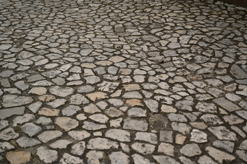 Old stone pavement texture with irregular cobblestones. Historic street surface background