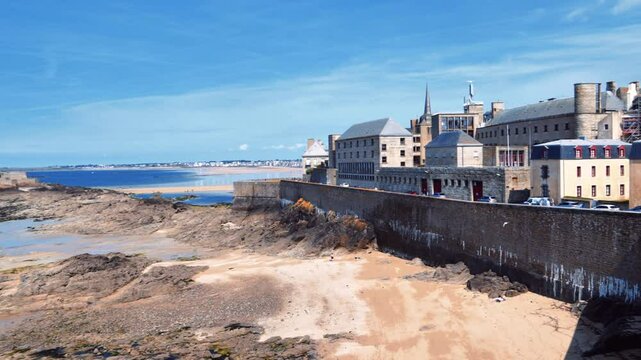 Skyline of the English Channel coast from fortress walls of the city of Saint-Malo during the ocean low tide against a blue sky. View of the old fortress National Fort. La Manche, Brittany, France