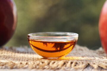 Apple cider vinegar in a glass bowl with fresh red apples