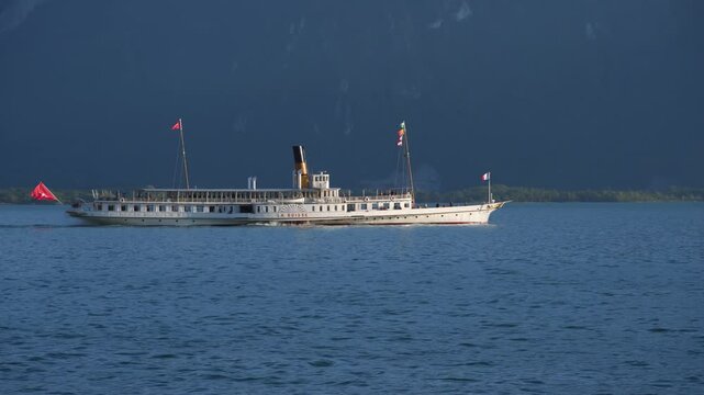 Montreux, Switzerland - May, 30 2019: Beautiful summer evening landscape of Lake Geneva with picturesque shores and pleasure ship against the backdrop of the green slopes of the Alps, Switzerland. 4K 